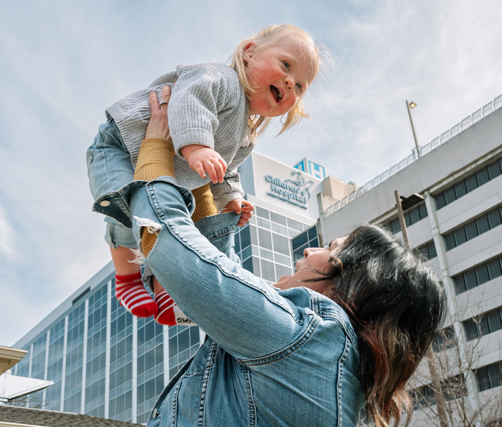 Child being lifted high in the air outside the Children's Hospital